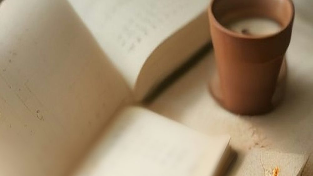 An open blank planner with coffee and a gold pen on a cozy knit blanket