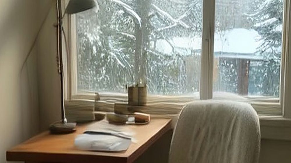 A cozy winter home office by a frosted window with a knit throw over the chair